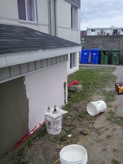 White acrylic coating being applied over a patched foundation.